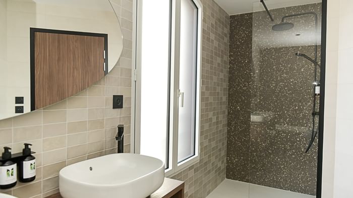 Salle de bain élégante avec douche vitrée et lavabo ovale à l'Hôtel Rivella.