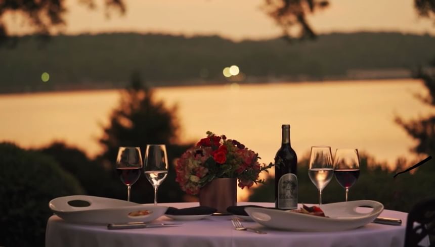 romantic dining table with wine overlooking sunset over lake