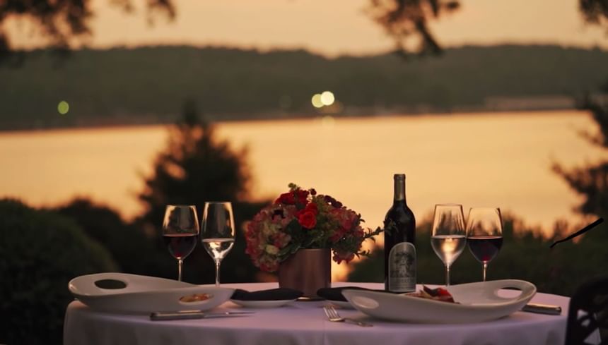 Romantic dinner table with wine glasses and flowers beside the sunset lake at Clemson University Conference Center & Inn