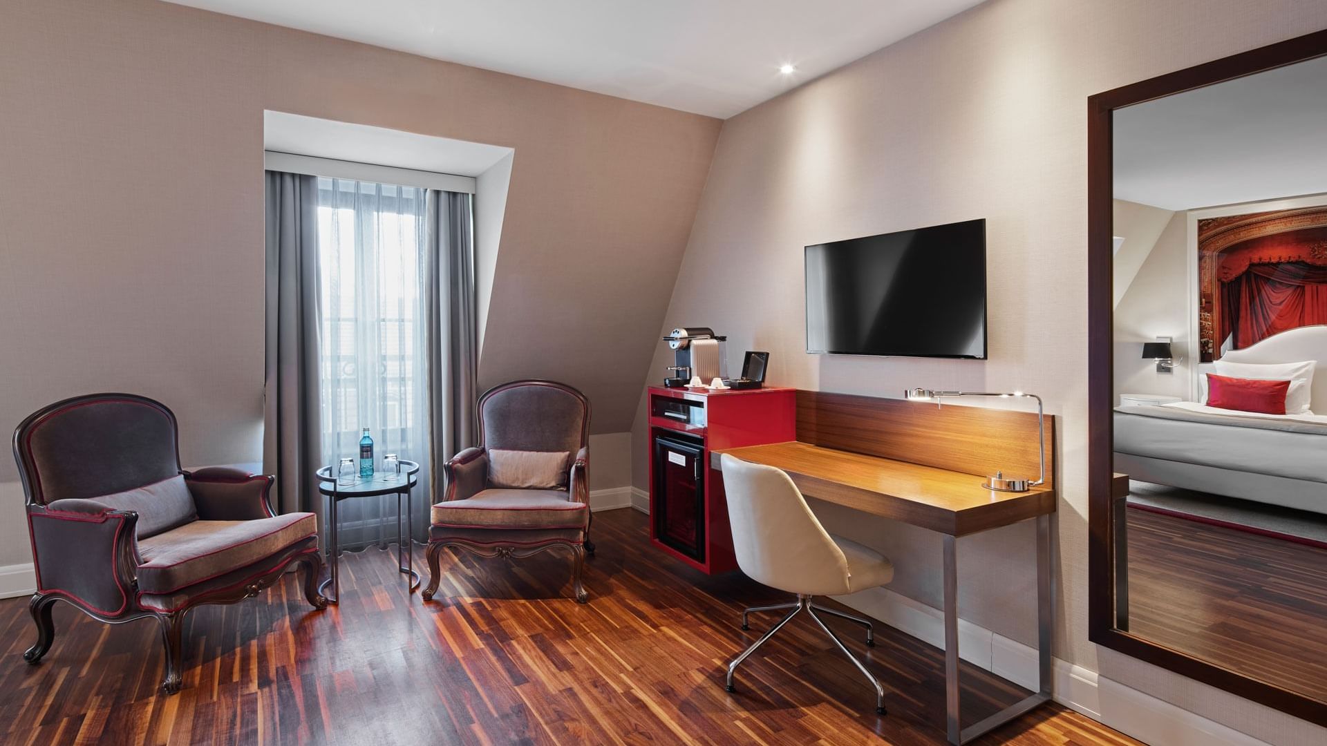 Moderner Arbeitsbereich mit TV und Espressomaschine in der Junior Suite des Titanic Gendarmenmarkt Berlin.