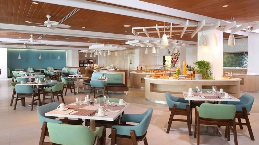 Modern tables by a buffet under hanging lamps surrounding teal chairs in verandah at Warwick Paradise Island Bahamas