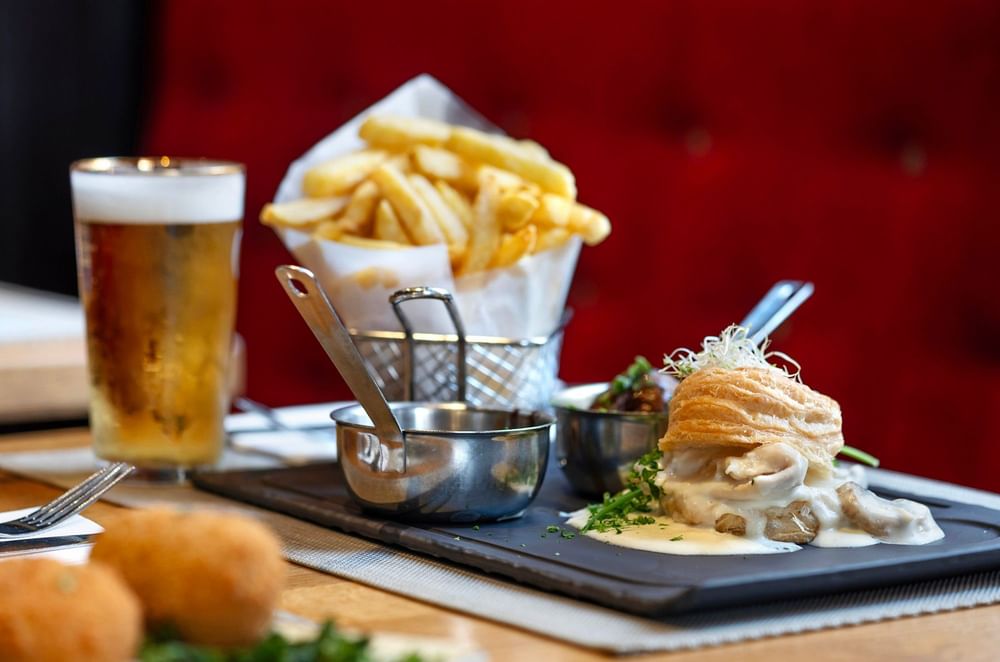 Vol-au-vent with fries and a glass of beer on a black slate tray at Hotel Barsey by Warwick