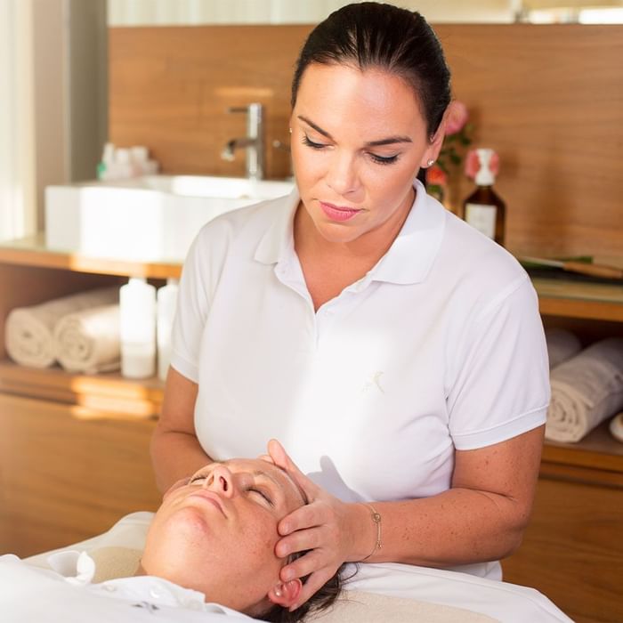 A therapist giving a face massage at Falkensteiner Hotels