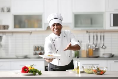 Chef posing with dish prepared in kitchen at Azalai Hotel Dakar