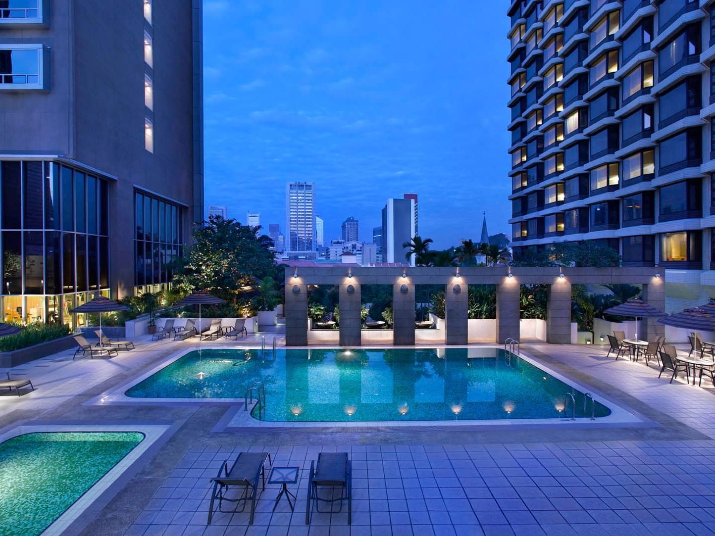 Outdoor swimming pool area at night in Carlton Hotel Singapore