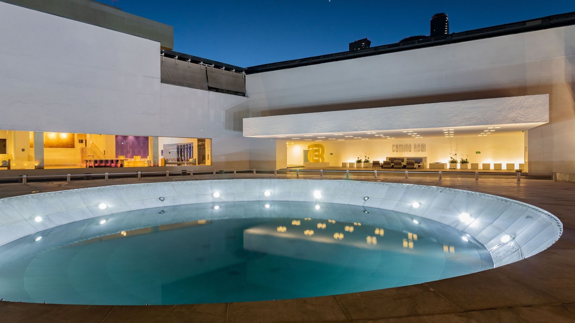 Modern circular water feature illuminated at night with white building at Camino Real Polanco Mexico