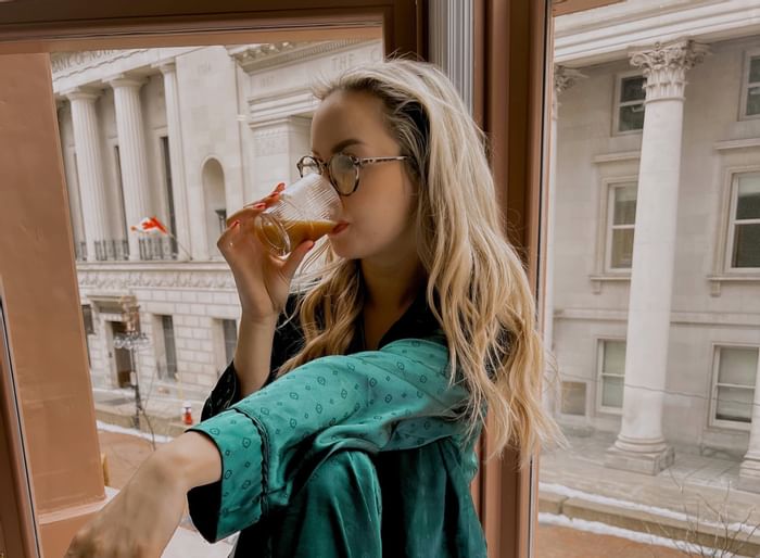 Lady drinking a coffee leaning to a window at ReStays Ottawa