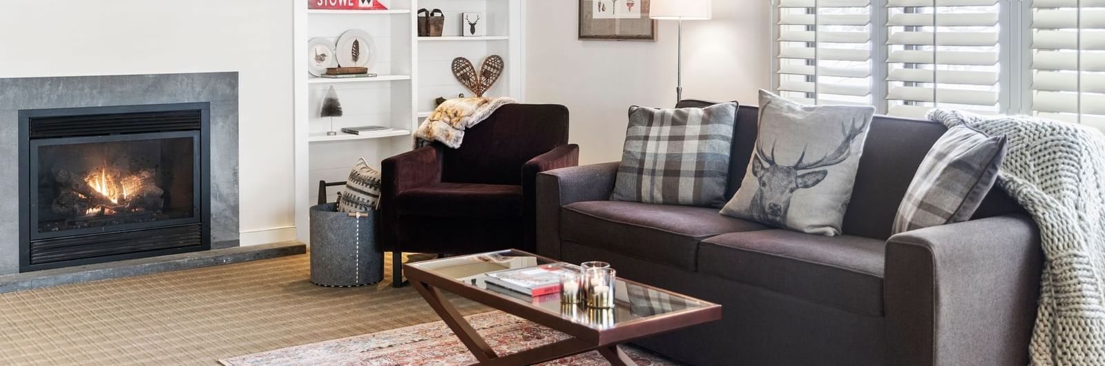 Wall-mounted TV, shelves, and fireplace beside the cozy living area of a luxury room at Topnotch Stowe Resort
