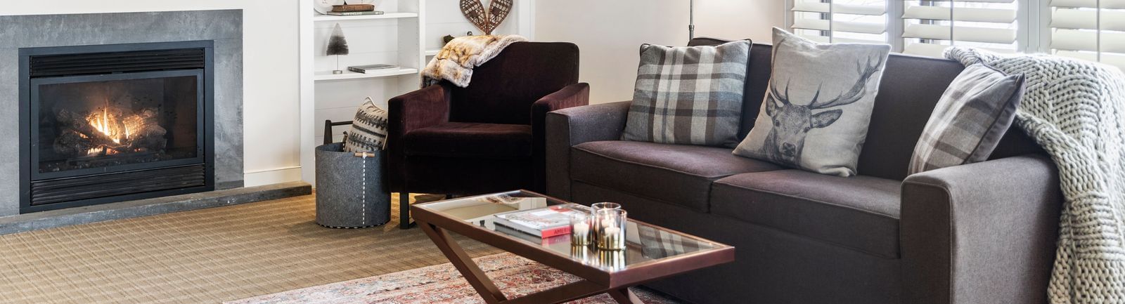 Wall-mounted TV, shelves, and fireplace beside the cozy living area of a luxury room at Topnotch Stowe Resort