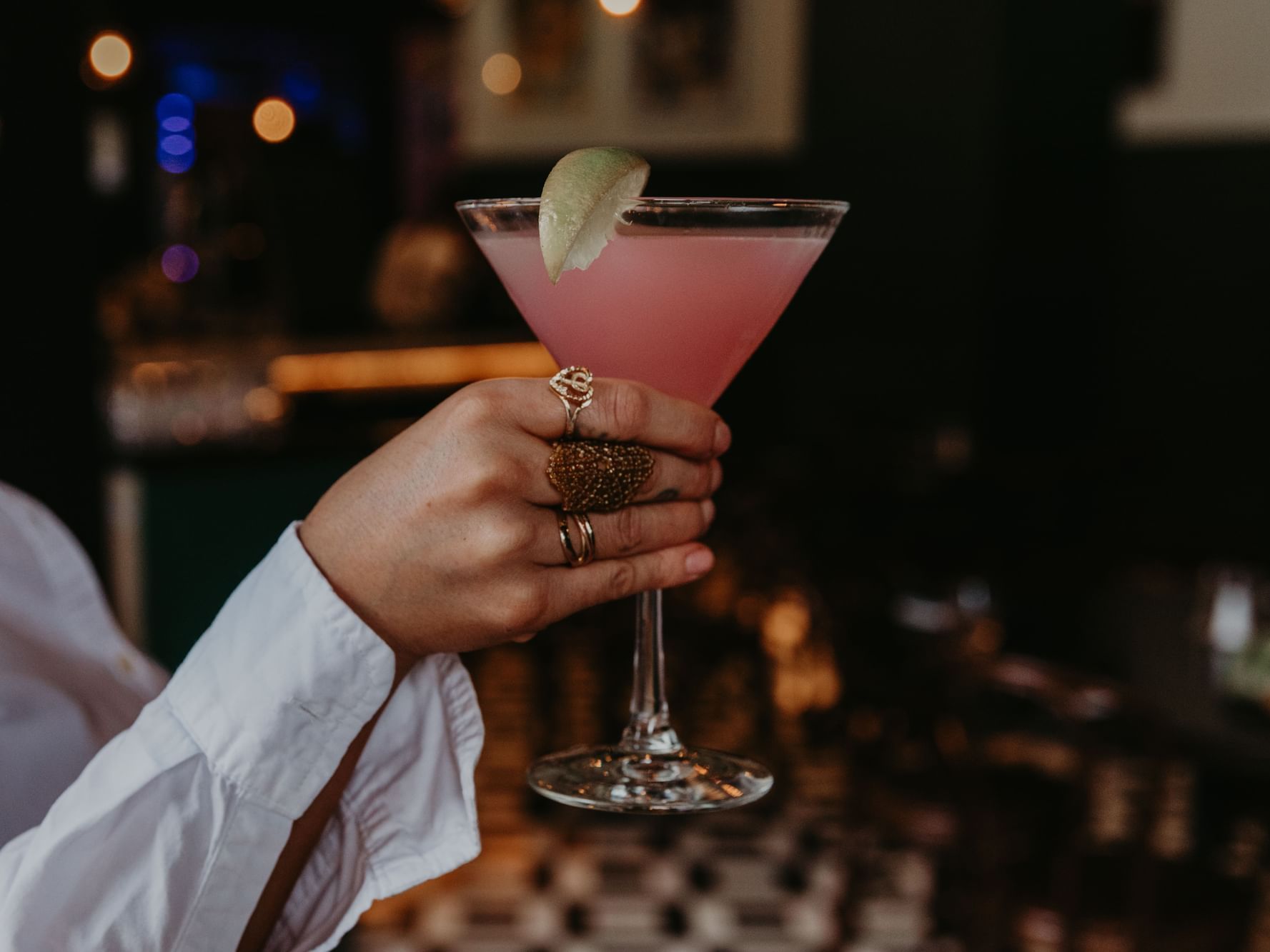 A hand holding a pink cocktail 