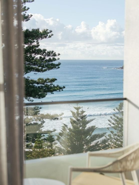Ocean View Two Bedroom at Elysium Hotels, balcony view framing pine trees and rolling waves along the coast