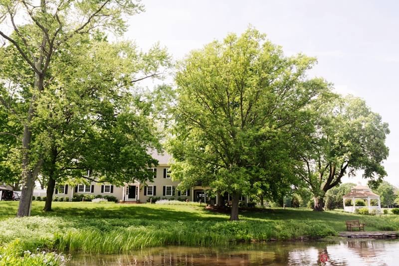 Scenic pond view with lush green trees and historic building at Aramark Chauncey Conference Center