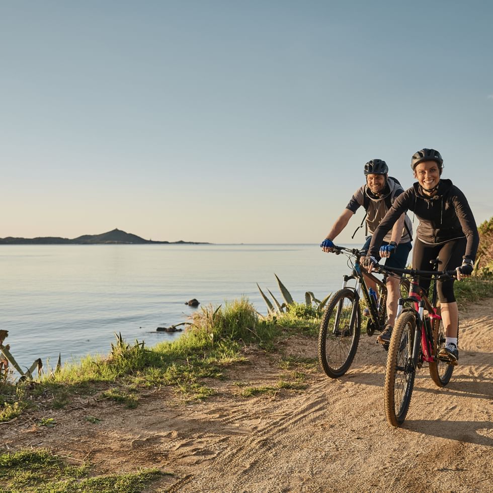 A couple cycling by a river near Falkensteiner Hotels