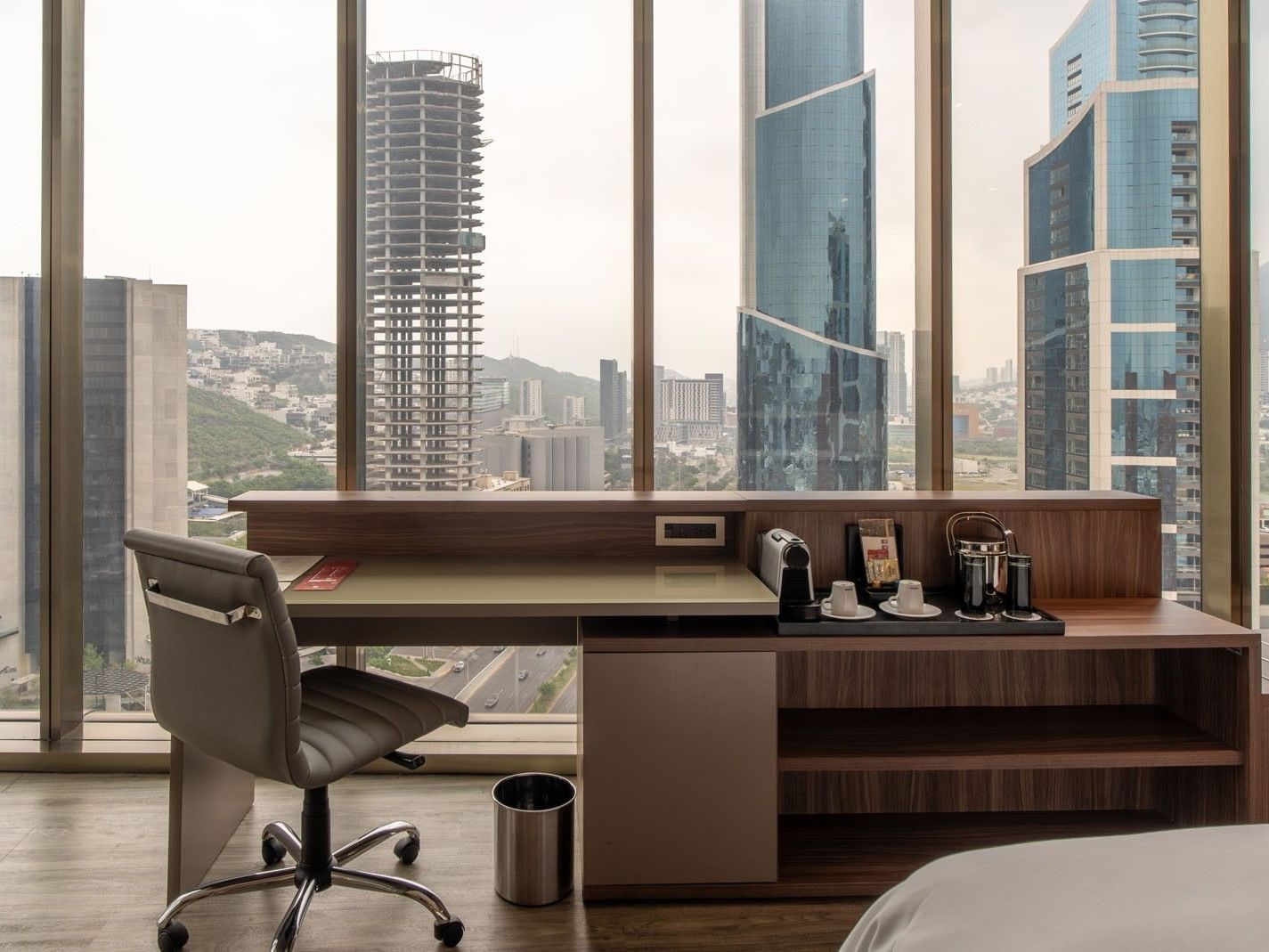 King Junior Suite workspace a wooden desk & a panoramic view of city towers at Camino Real Fashion Drive, Monterrey