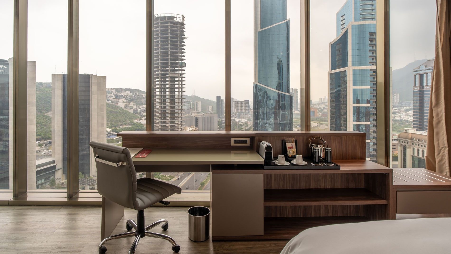 King Junior Suite workspace a wooden desk & a panoramic view of city towers at Camino Real Fashion Drive, Monterrey