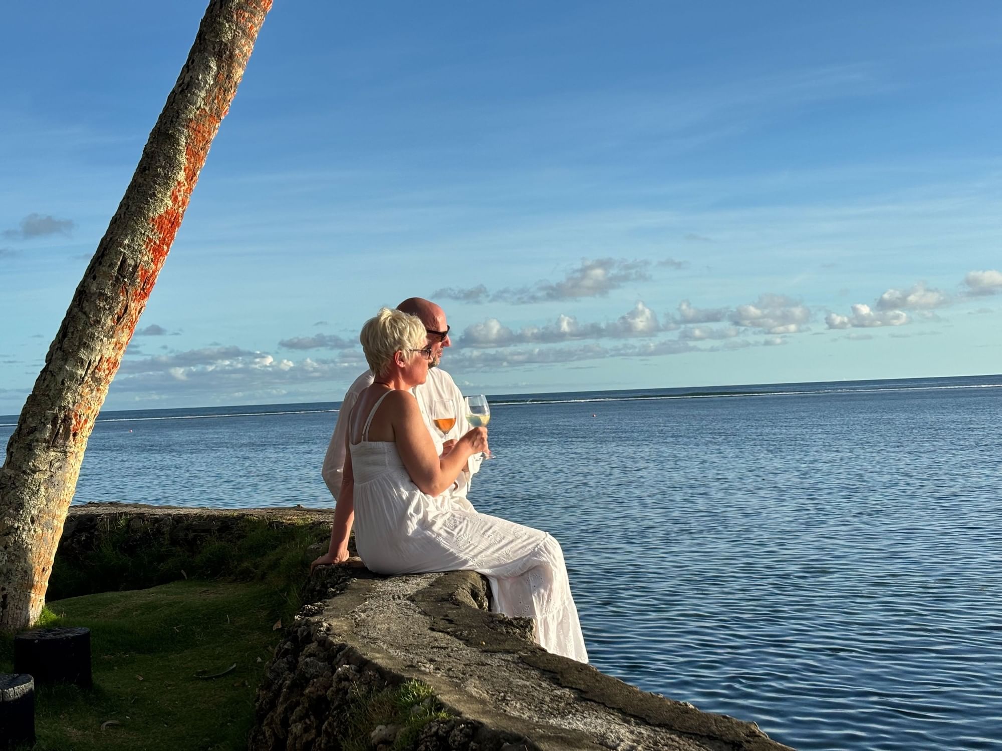 Couple in white sitting by the ocean, wine in hand at Warwick Fiji Resort and Spa - Redesign