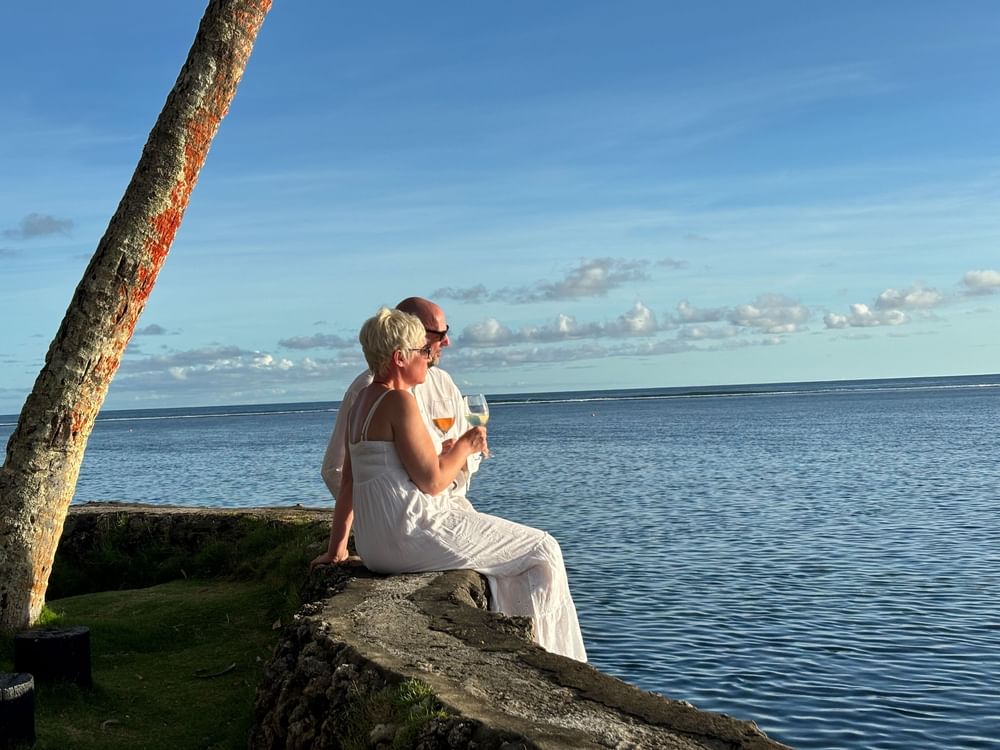 Couple in white sitting by the ocean, wine in hand at Warwick Fiji Resort and Spa - Redesign