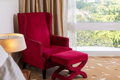 A red armchair and ottoman offer a cozy spot to relax in a room at the Royal on the Park Hotel