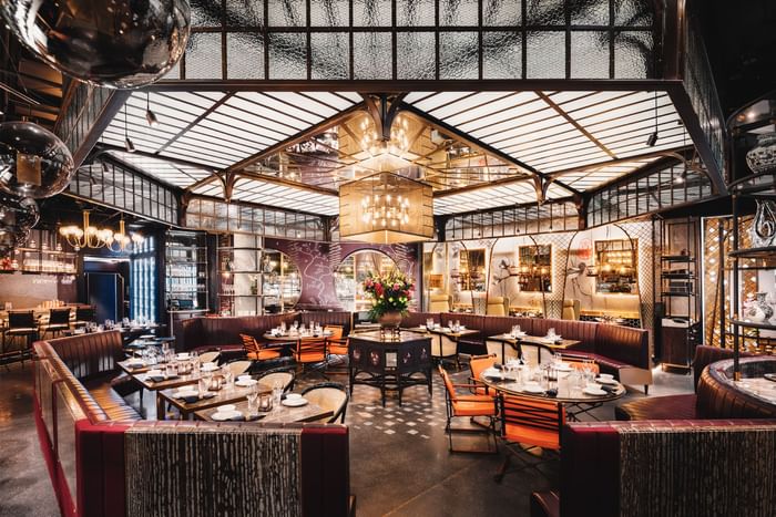 Mott 32 restaurant with intricate ceiling design, booths, and tables set with fine dining ware.