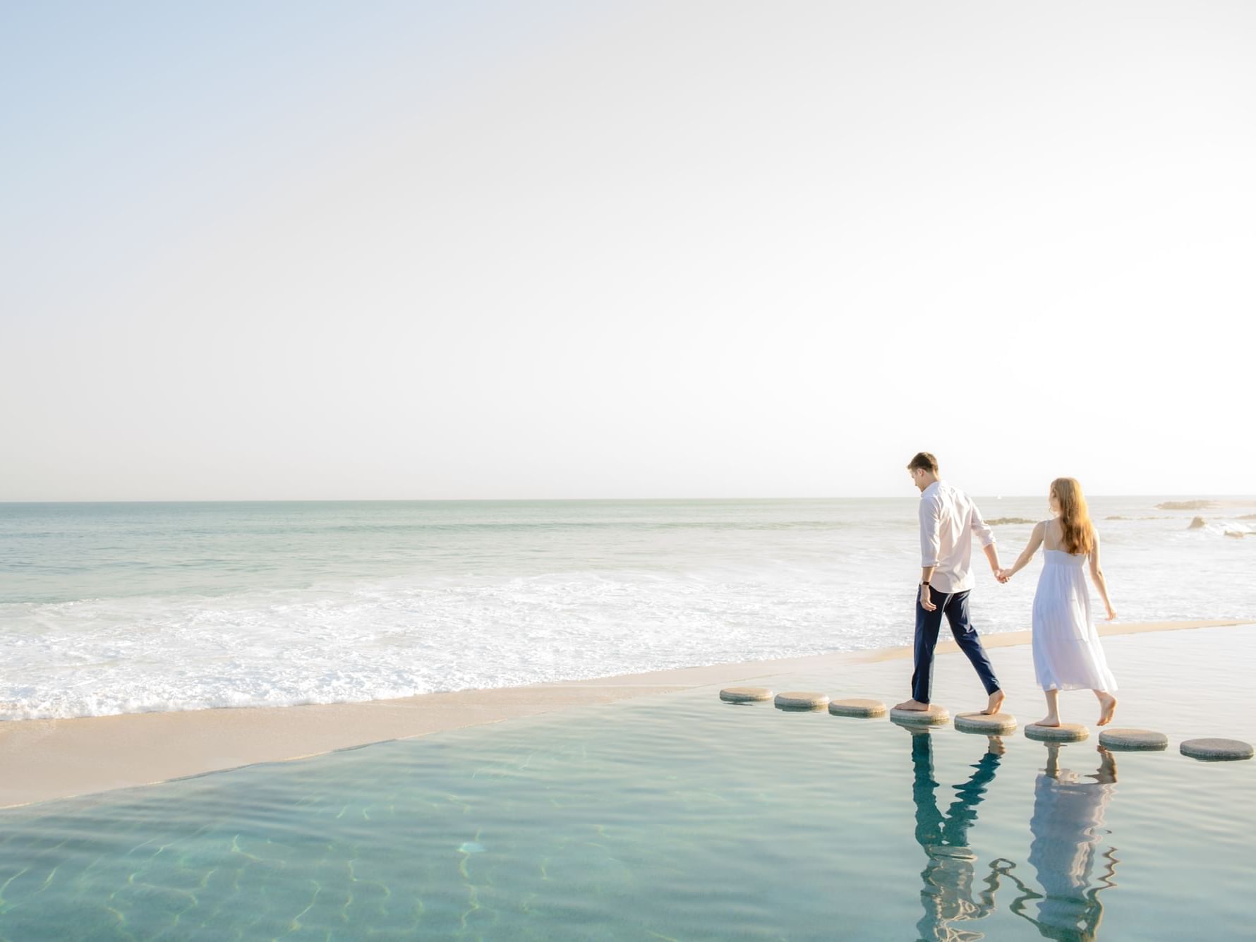 A couple walking on Stepping stones on the pool at Los Cabos