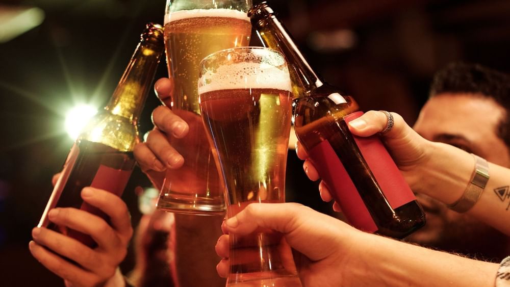 Friends toasting with beer bottles and glasses in a warm, festive atmosphere for end-of-year celebrations.
