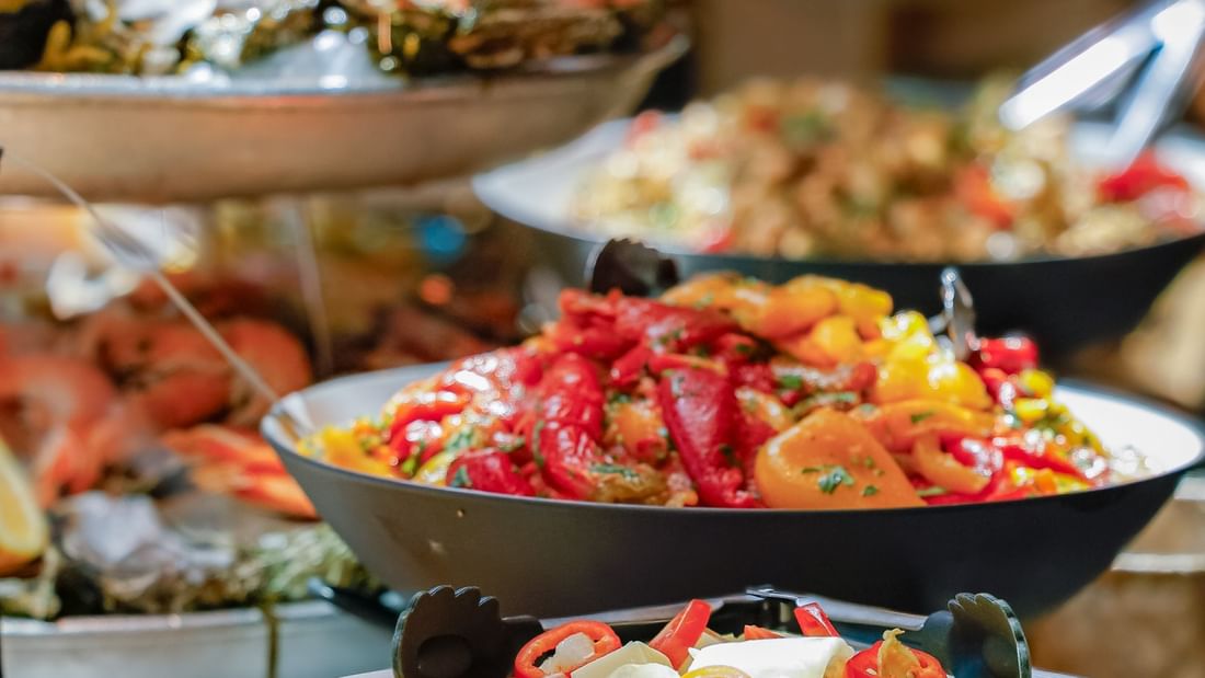 Multiple bowls of assorted seafood and vegetables on a buffet table.