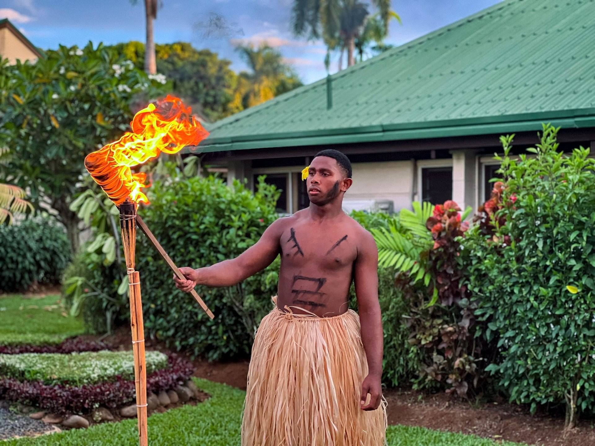 Performer in traditional grass attire participating in a sunset fire ceremony at TokaToka Resort Nadi Fiji