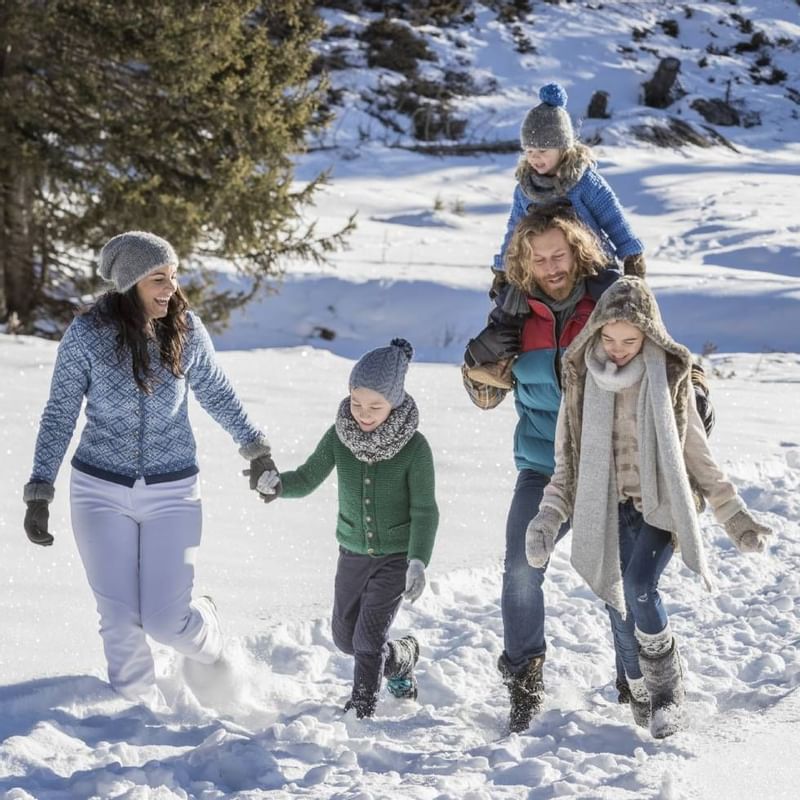 A family enjoying a walk on the snow near Falkensteiner Hotels