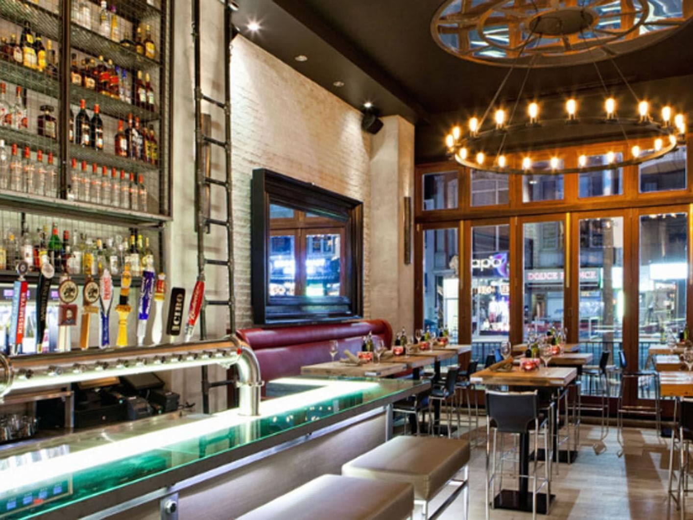 Cibo Wine Bar Yonge St with stools, tables set for dining, and a liquor shelf near Hotel X Toronto