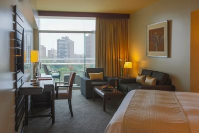 TV, work desk & seating area by the cozy bed in Junior Suite with a city view at Hotel Los Delfines & Casino