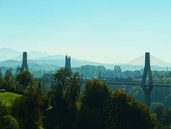 Pont de la Poya bridge spanning a river amid greenery and distant mountains near Hotel des Innovations