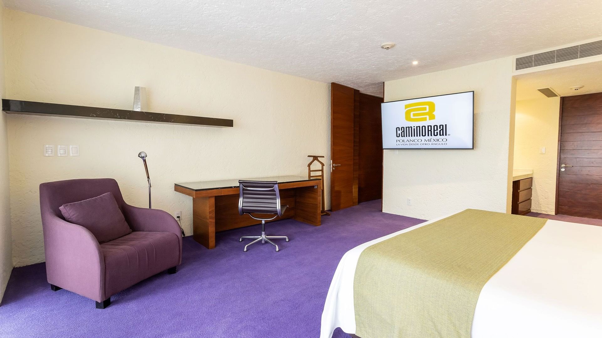 King Viceroys Suite featuring a purple armchair, wooden desk, and a wall-mounted TV at Camino Real Polanco Mexico