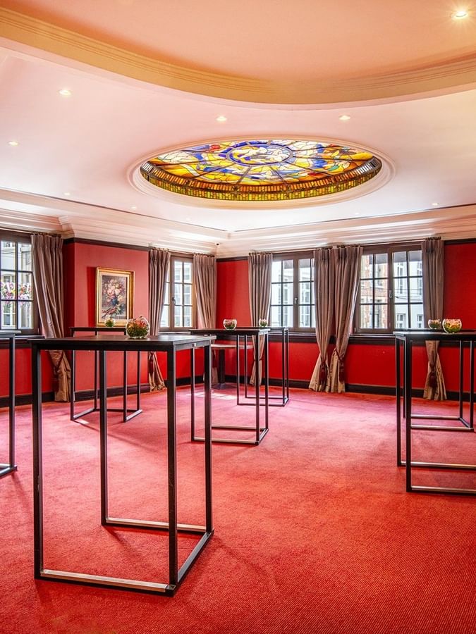 L'élégante salle de réception « Salon Grand-Place », avec tapis rouge et tables en verre, au Warwick Grand-Place Brussels.