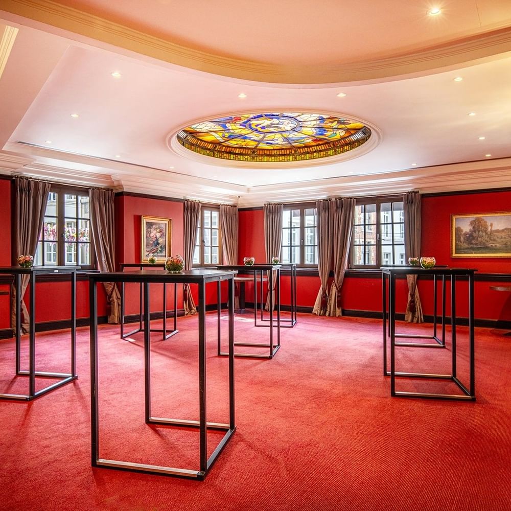 L'élégante salle de réception « Salon Grand-Place », avec tapis rouge et tables en verre, au Warwick Grand-Place Brussels.