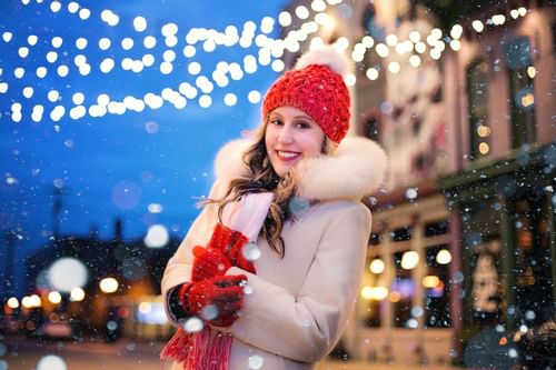 Woman in winter clothes in downtown area with Christmas lights
