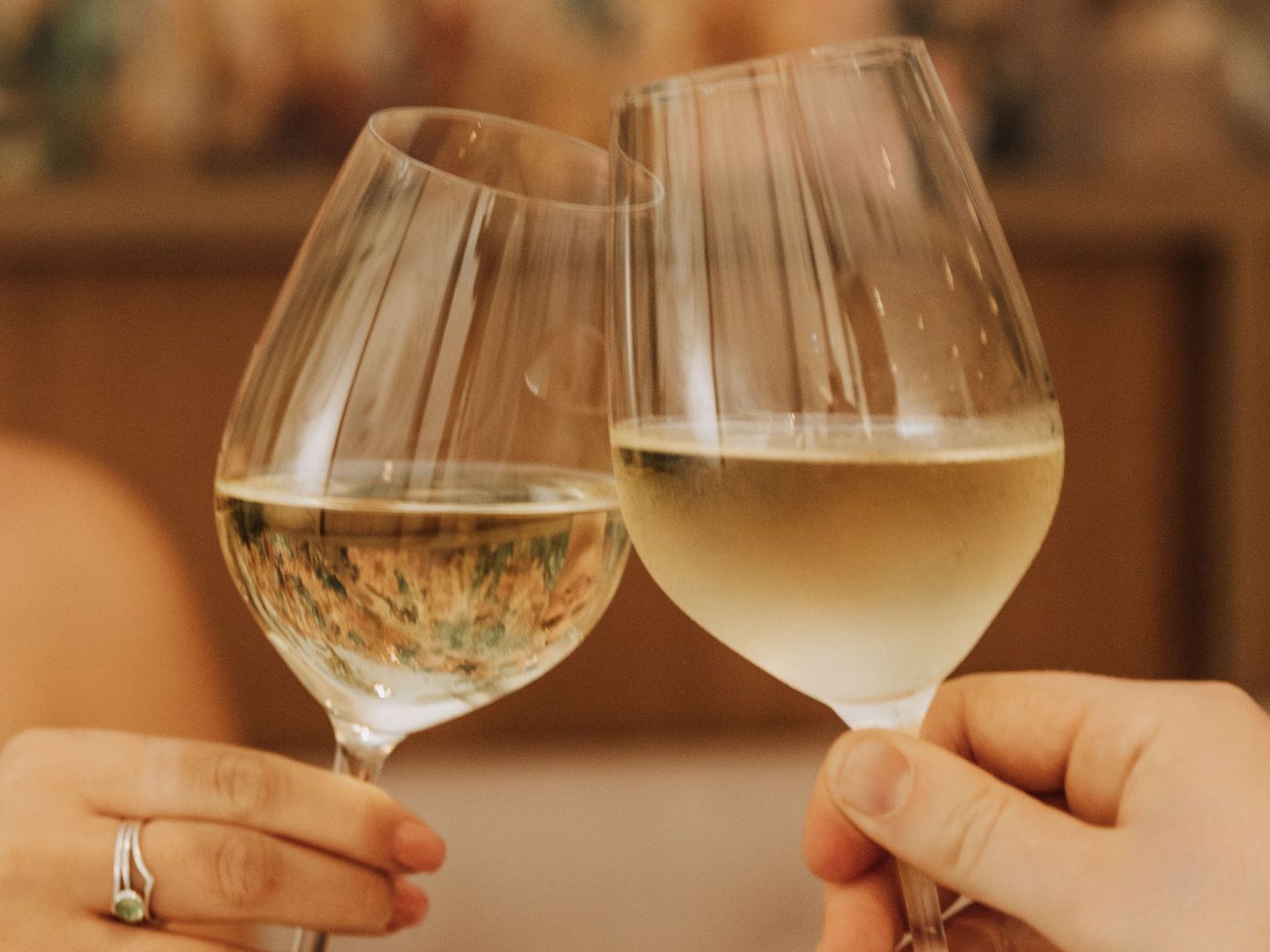 Close-up of two people making a toast with wine glasses during a romantic dinner at Amora Brisbane Hotel