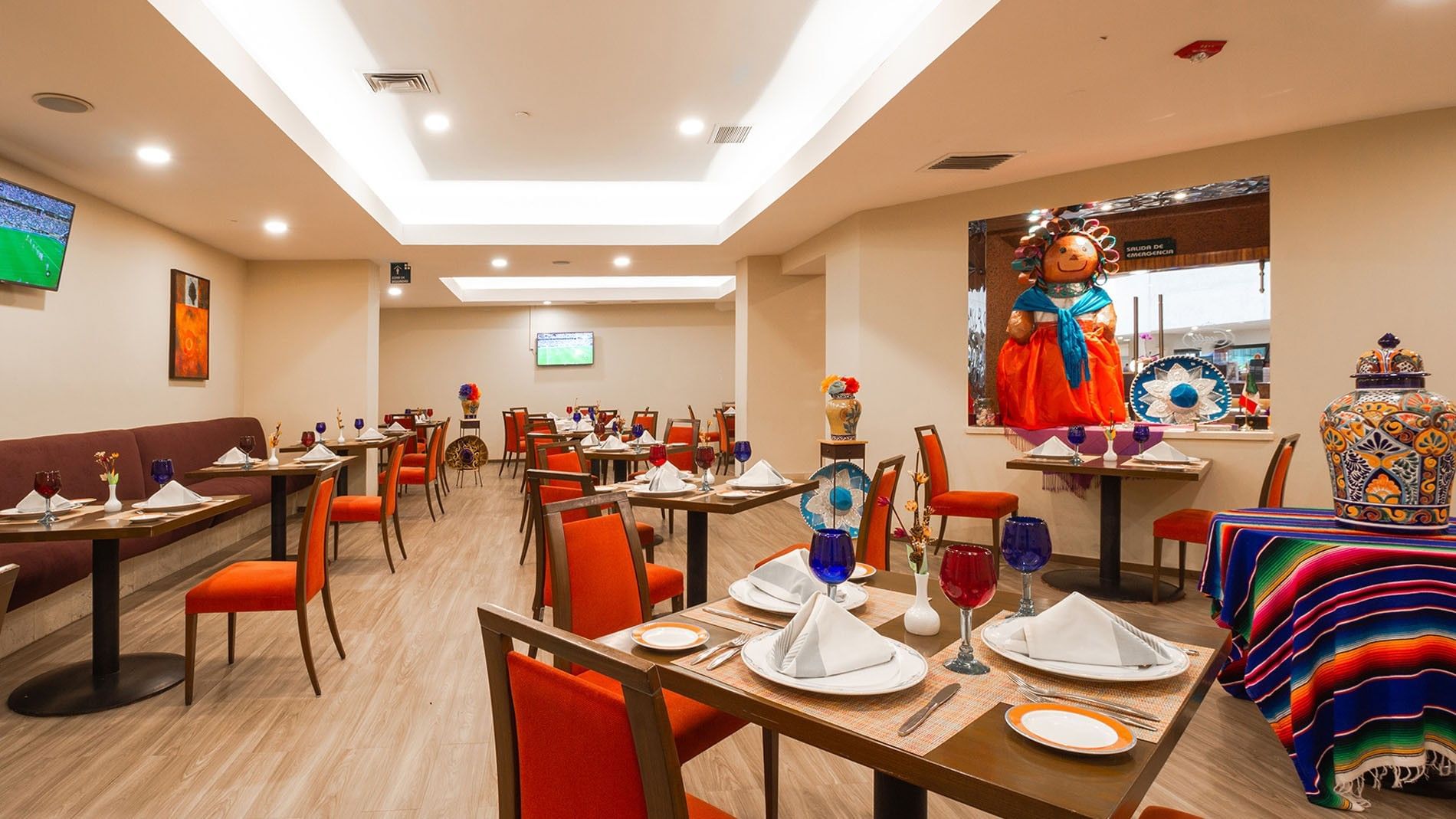 Modern dining room with colorful decor and sports TV screens at Camino Real Aeropuerto Mexico