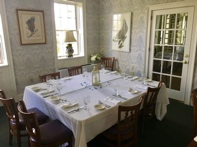 Private dining room at Simsbury 1820 House, long table set with glassware surrounded by wooden chairs and bird prints