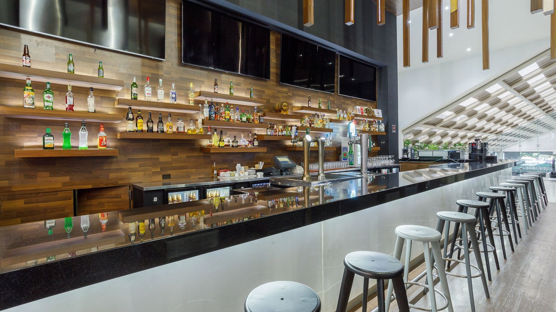 Stock Bar with black counters, high stools, and multiple TV screens at Real Inn Tijuana