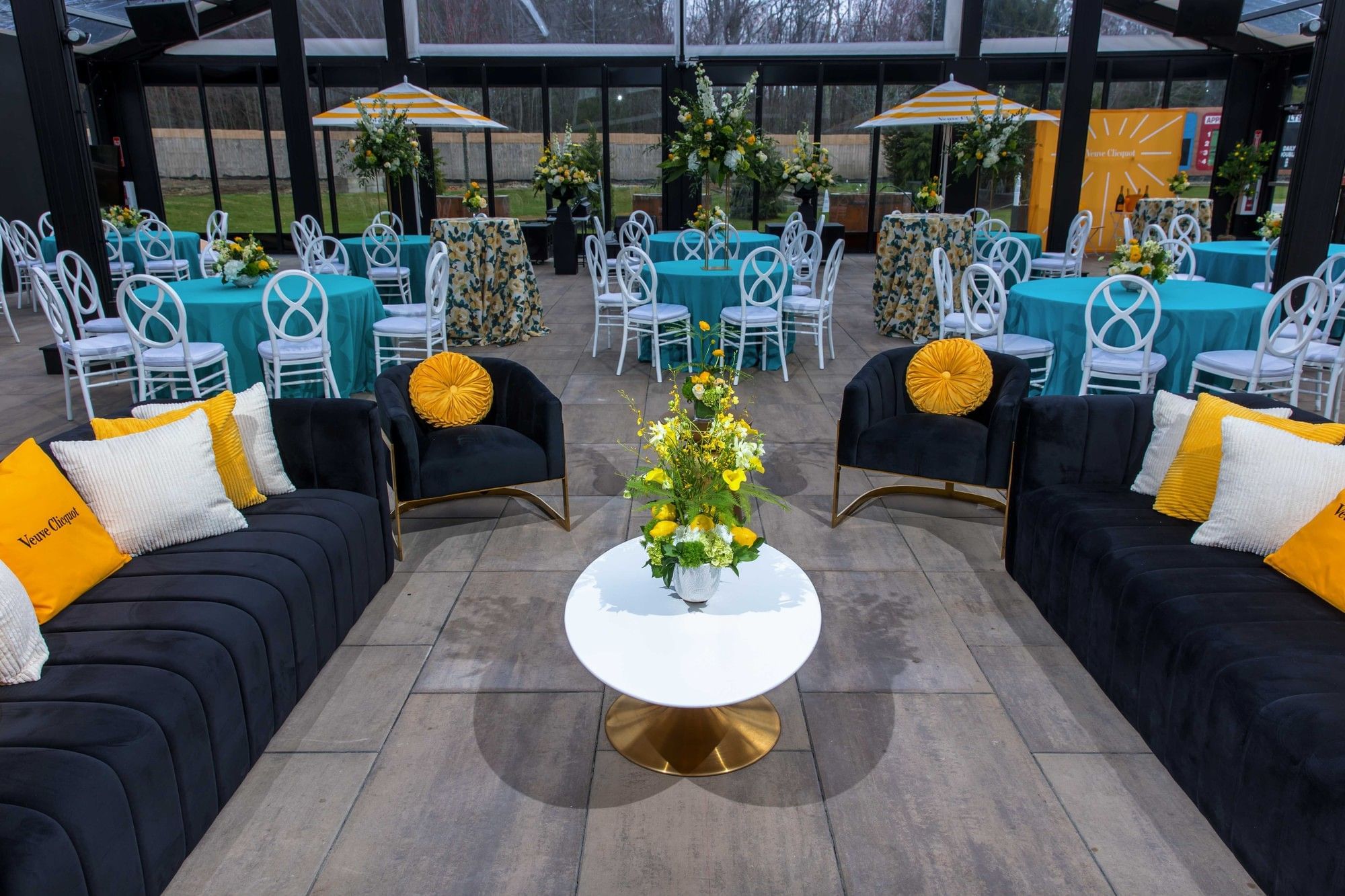 Cozy lounge seating area with dark velvet couches and white coffee table inside the modern event glasshouse at The Brook