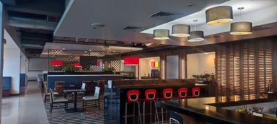Restaurant with sleek furniture, bar with red accents and warm lighting at D Sabana Hotel