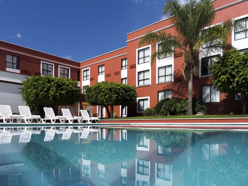 Outdoor swimming pool with hotel Exterior at Fiesta Inn Hotels
