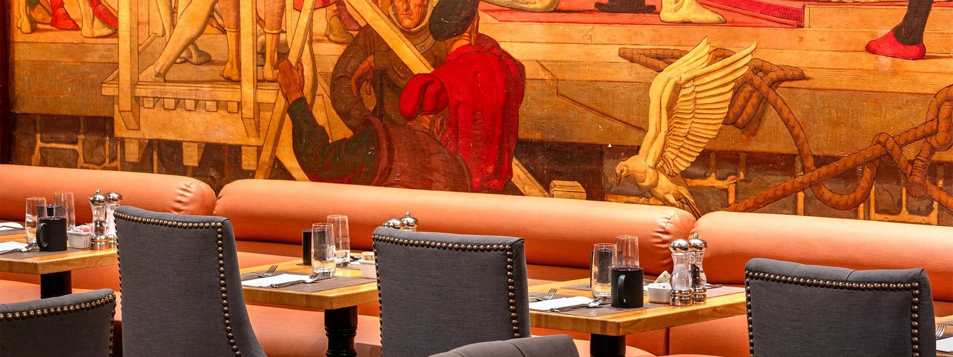 Upscale dining area with gray studded chairs and vibrant wall illustrations in Murals on 54 at Warwick New York