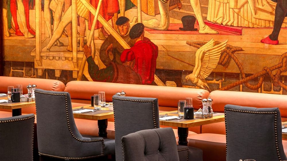 Upscale dining area with gray studded chairs and vibrant wall illustrations in Murals on 54 at Warwick New York