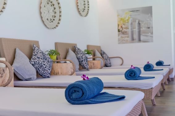 A row of beds, each equipped with blue towels and pillows in the spa at Grand Park Kodhipparu, Maldives