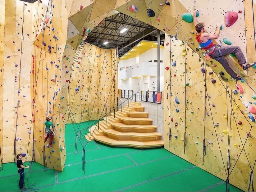 A person scaling a climbing wall inside Calgary Climbing Centre near Acclaim Hotel Calgary