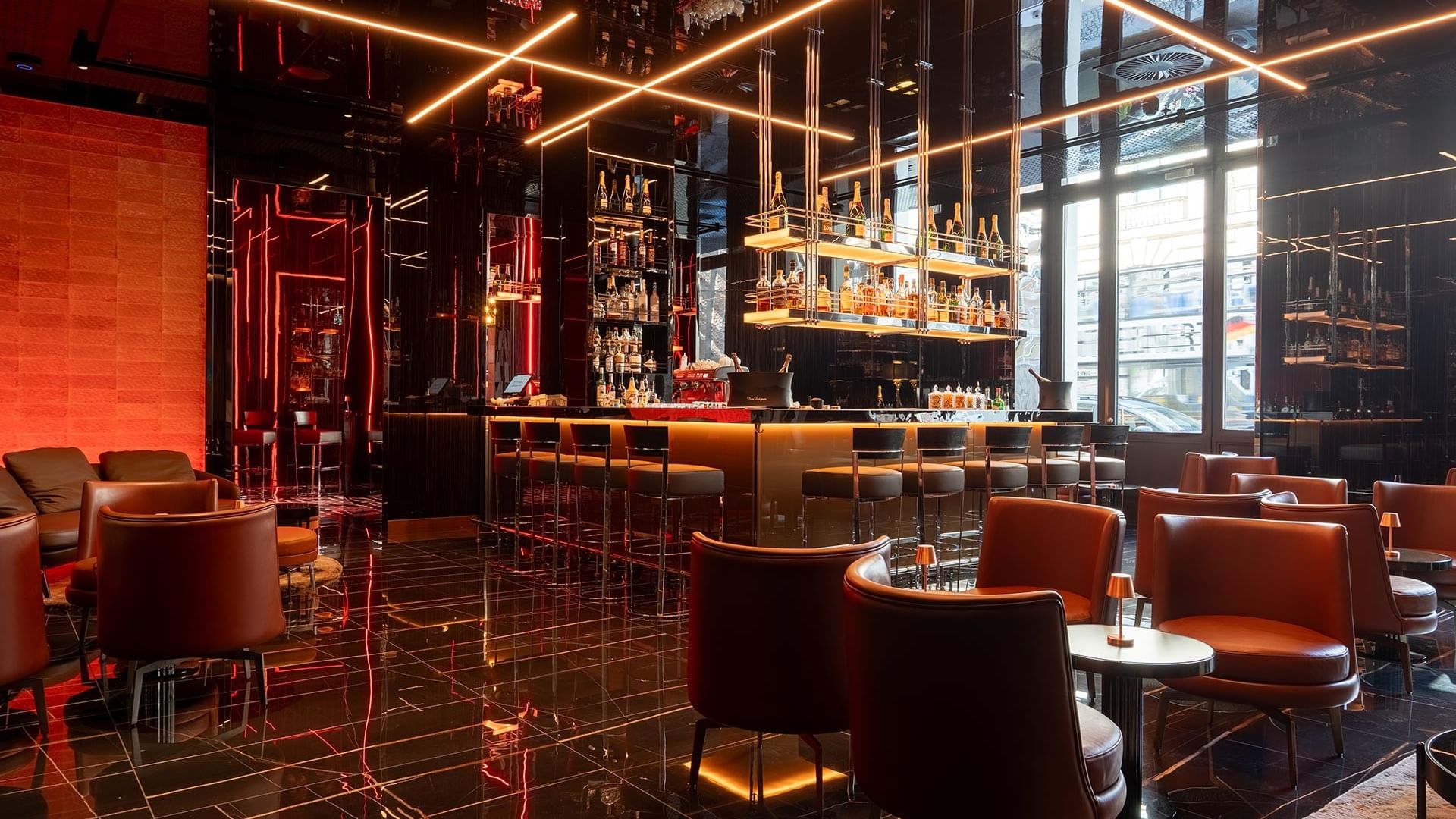Moderne Bar mit orangefarbenen Ledersesseln und goldenen Lichtakzenten im Titanic Gendarmenmarkt Berlin