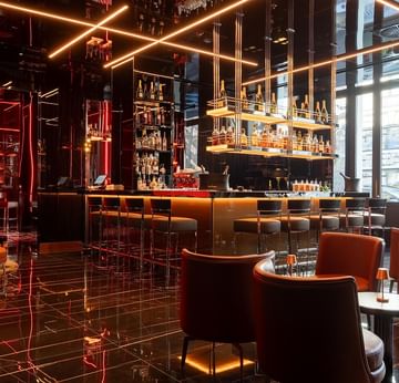 Moderne Bar mit orangefarbenen Ledersesseln und goldenen Lichtakzenten im Titanic Gendarmenmarkt Berlin