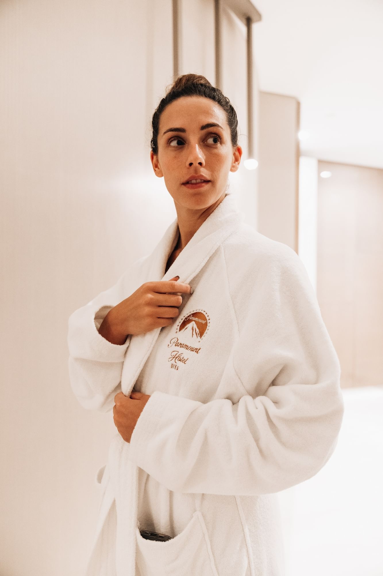 Lady in a robe with hotel sign posing by Pause Spa at Paramount Hotel Dubai