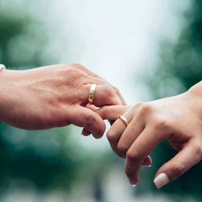Bride and groom with matching wedding bands holding hands